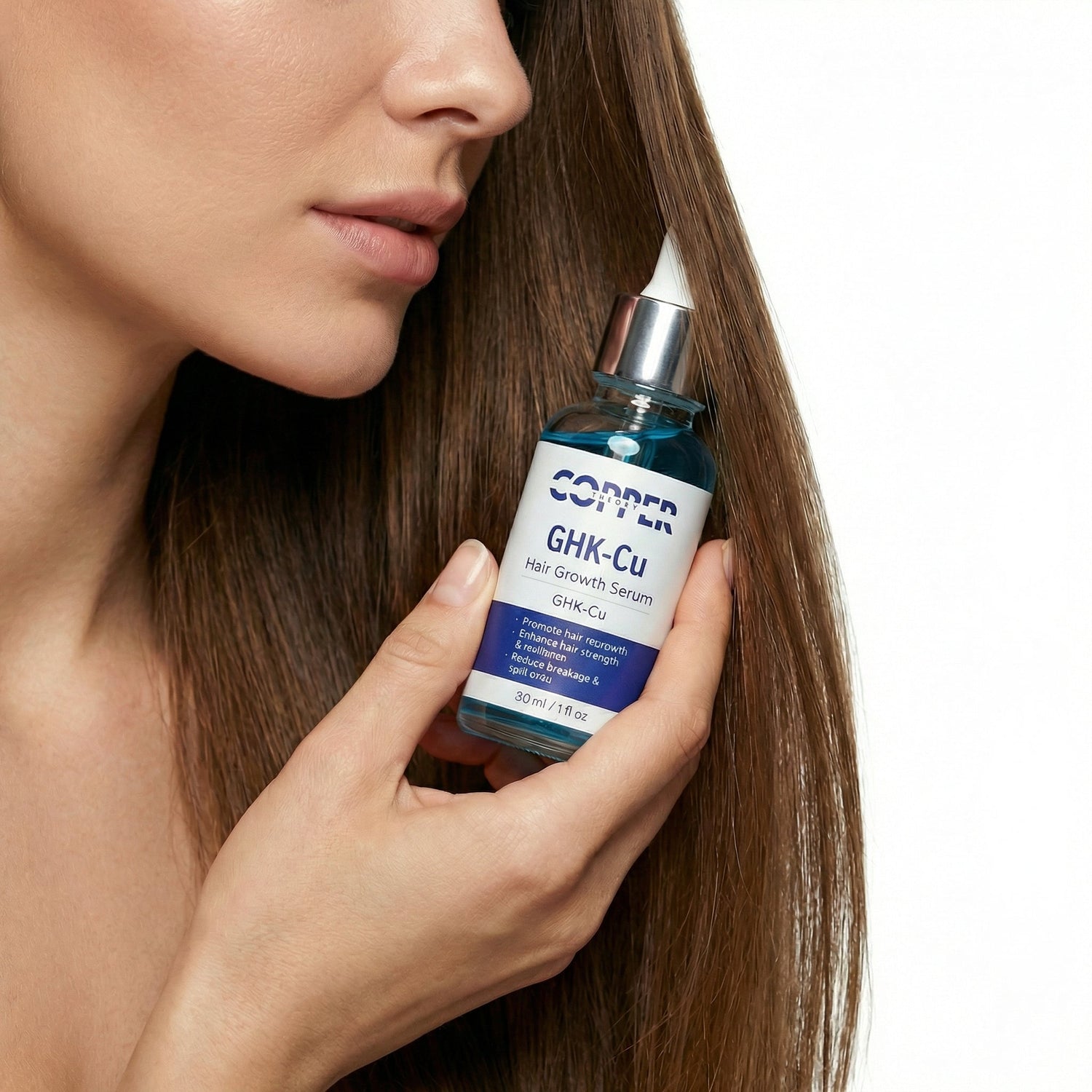 Copper Theory GHK-CU copper peptide hair serum held beside long brown hair on clean white background